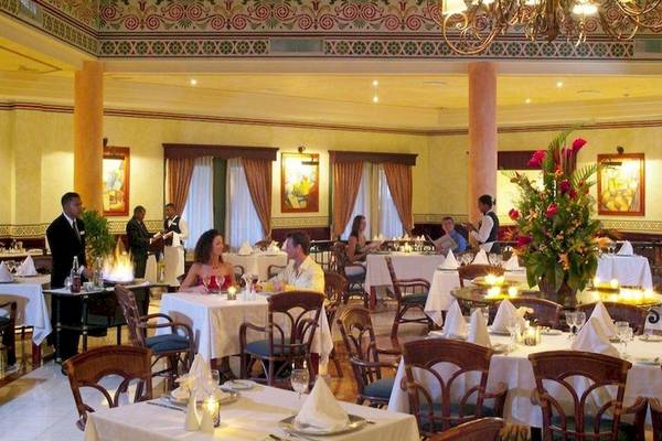 Innenansicht eines eleganten Restaurants im Bahia Principe Grand Bavaro Hotel mit Gästen an Tischen, die serviert werden.