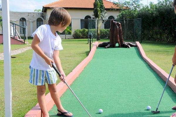 Zwei Kinder spielen Minigolf im Außenbereich des Bahia Principe Grand Bavaro Hotels.