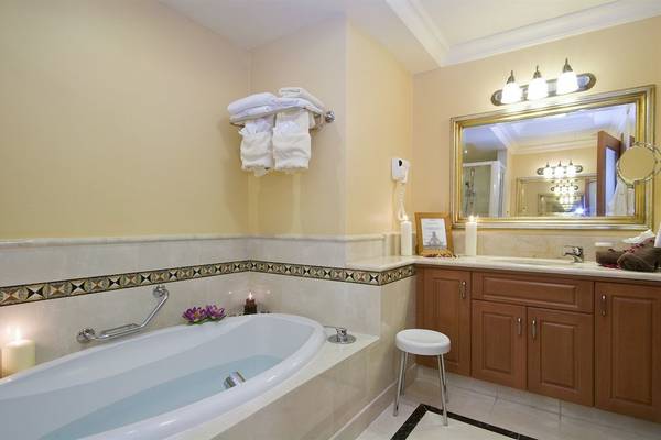 Badezimmer im Radisson Blu Resort & Spa, Malta Golden Sands mit Badewanne, Handtüchern und Badezimmermöbeln.