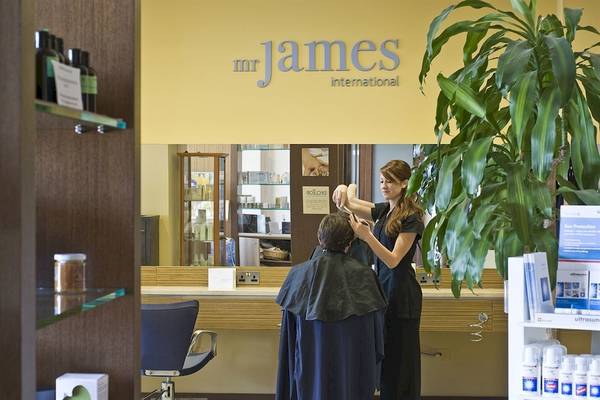Friseursalon mit Frau, die einem Mann die Haare schneidet, Schild mit Mr. James International.