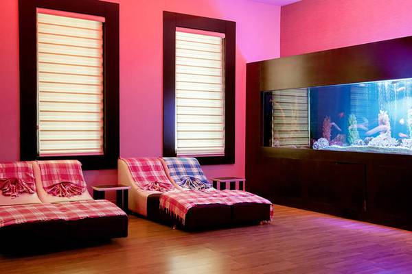 Hotellounge mit Aquarienwand und zwei roten Loungesofas mit Plaids
