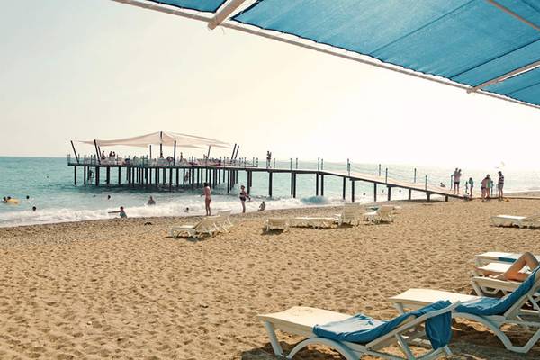 Strand mit Lounge-Stühlen und einer Brücke, die zum Meer führt, Seaden Sea World Resort & Spa