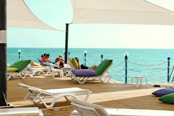Foto von der Terrasse des Seaden Sea World Resort & Spa mit Sonnenliegen, Gästen und Blick auf das Meer.