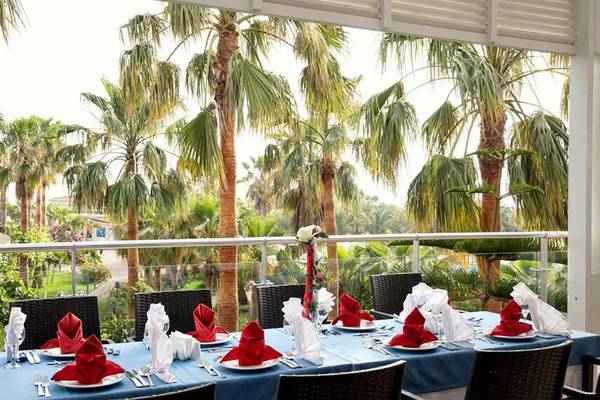 Balkon mit Tisch für Essen im Seaden Sea World Resort & Spa mit Blick auf Palmen.