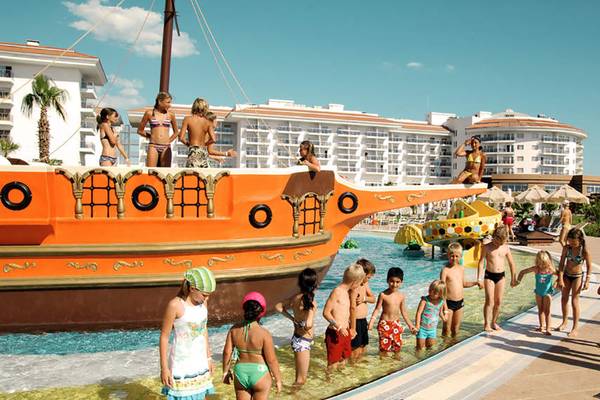 Kinder spielen im Schwimmbad des Seaden Sea World Resorts vor einem großen Piratenschiff.