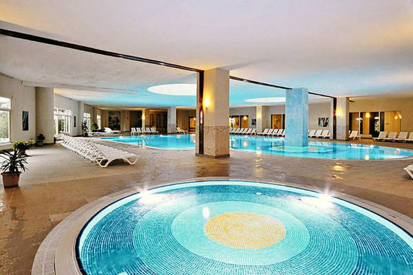 Innenpool des Seaden Sea World Resort & Spa mit zwei Schwimmbecken und Sonnenliegen.