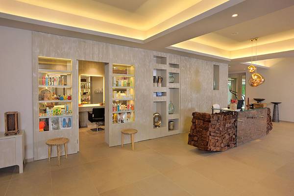 Empfangsbereich des Nelia Beach Hotel & Spa mit Holztheke, Regalen und Möbeln.