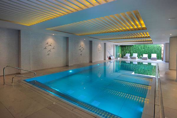 Innenpool des Nelia Beach Hotel & Spa mit beleuchteten Wänden und Liegestühlen.