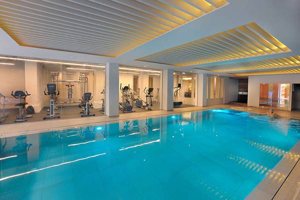 Innenpool des Nelia Beach Hotel & Spa mit Fitnessgeräten und einer schwimmenden Person