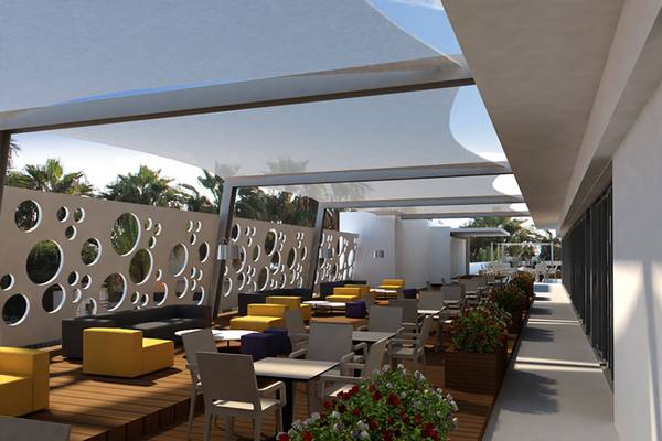 Terrasse des Nelia Beach Hotel & Spa mit Tischen, Stühlen und Pflanzen