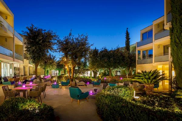 Außenbereich des Valamar Argosy Hotels mit blauen Lichtern, Tischen, Stühlen und Pflanzen bei Nacht.