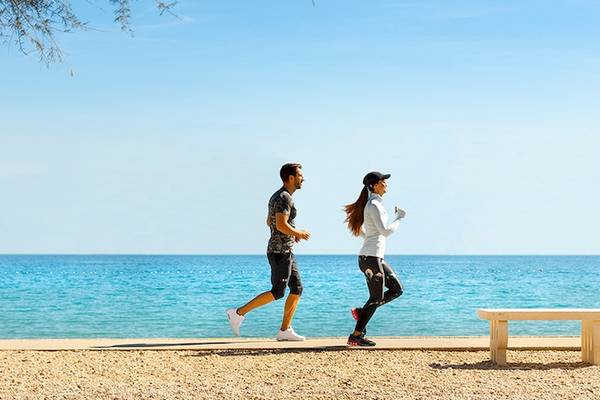 Paar, das am Strand neben dem Hotel Valamar Argosy joggt.