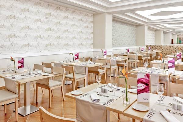 Innenansicht des Restaurants im Occidental Jandia Playa Hotel mit gedeckten Tischen und weißen Wänden.