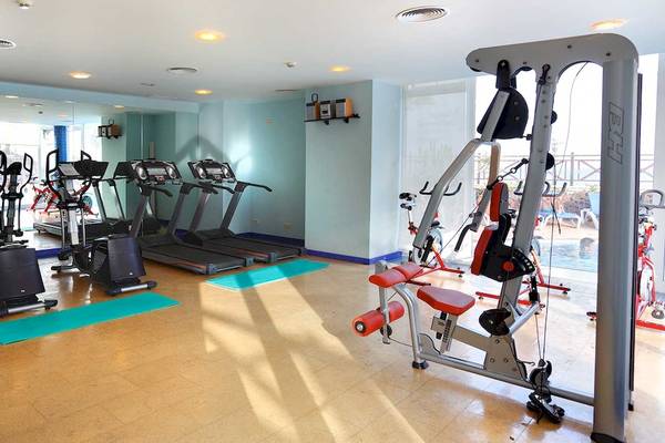 Fitnessstudio im Occidental Jandia Playa Hotel mit diversen Geräten und Spiegeln.