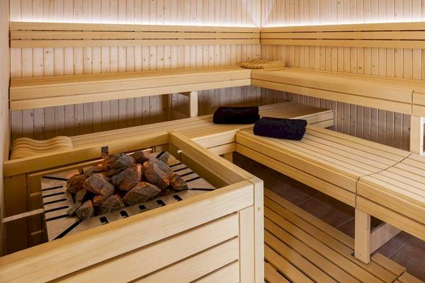 Holzsauna mit mehreren Sitzbänken und einem Holzofen im Occidental Jandia Playa Hotel.