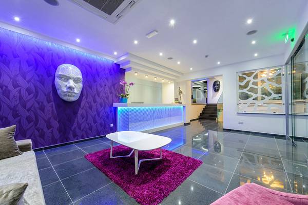 Lobby des Tasia Maris Sands Hotels mit violetten Wänden, einer weißen Couch und einem Tisch