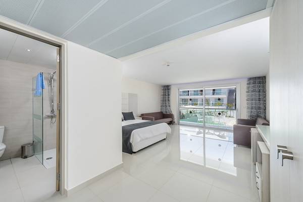 Ein modernes Hotelzimmer im Tasia Maris Sands mit einer Dusche, einem Bett und einem Sofa.