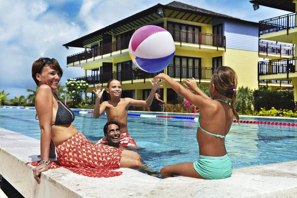 Familie am Pool im LionsDive Beach Resort, alle spielen mit einem Ball.