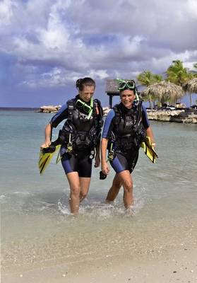 Zwei Taucherinnen gehen ins Wasser am LionsDive Strandresort.