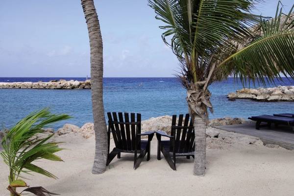 Strandszene mit zwei Stühlen unter Palmen und Blick auf das Meer, LionsDive Beach Resort