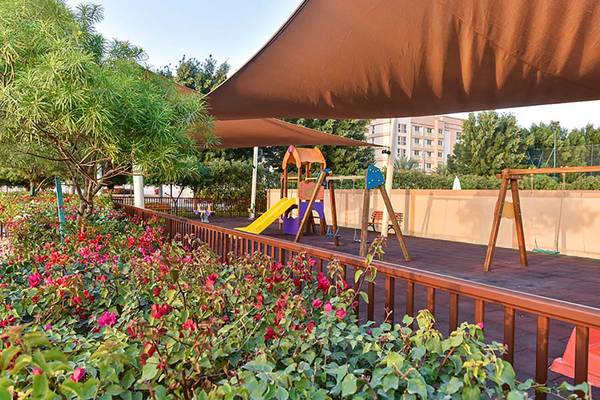 Kinderspielplatz im Hotel Jannah Hotels Resorts & Villas mit gelber Rutsche und Schaukeln.