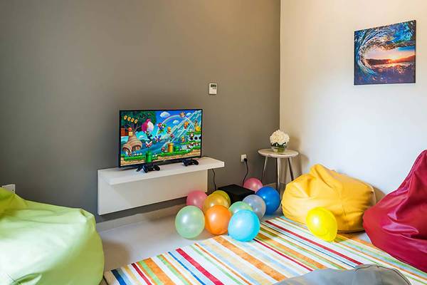 Kinderzimmer mit Fernseher und bunten Ballons auf einem bunten Teppich.