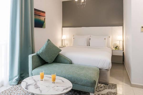 Schlafzimmer im Jannah Hotels Resorts & Villas mit Bett, Kissen, Nachttischen und Gemälde an der Wand.