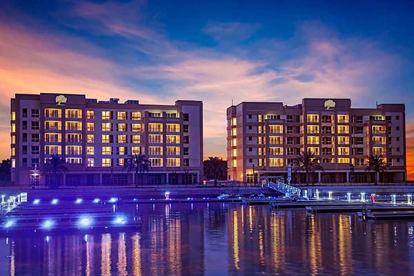 Jannah Hotels Resorts & Villas bei Sonnenuntergang mit leuchtenden Fenstern und Wasserreflexion.