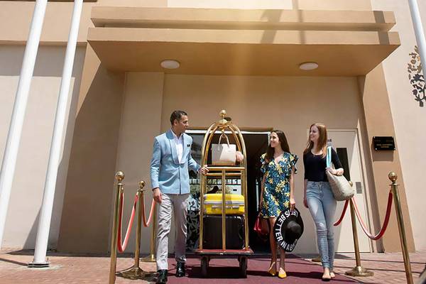 Eingang zu Jannah Hotels Resorts & Villas mit Gepäckwagen und Gästen