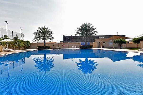 Ein großer Swimmingpool bei Jannah Hotels Resorts & Villas, umgeben von Palmen und Lounge-Stühlen.