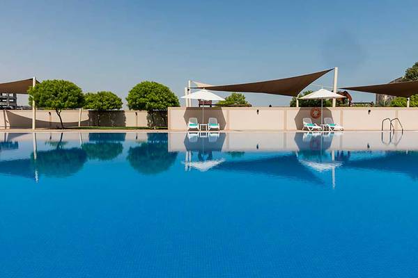 Außenbereich des Jannah Hotels Resorts & Villas mit einem großen Swimmingpool und Sonnenschirmen.