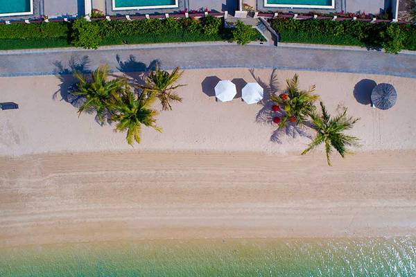 Oberflächenansicht eines Strandes mit Palmen und Sonnenschirmen bei Jannah Hotels Resorts & Villas.