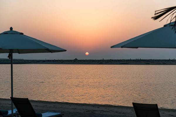 Sonnenuntergang am Strand mit Sonnenschirmen und Strandliegen