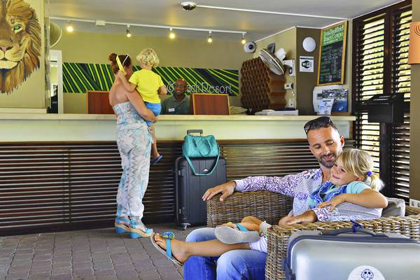 Familie am Empfang des LionsDive Beach Resorts, ein Mann und eine Frau mit zwei Kindern.