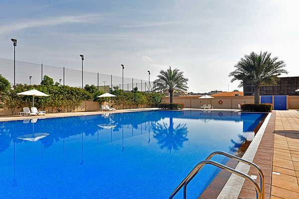 Ein großer Swimmingpool von Jannah Hotels Resorts & Villas mit Sonnenliegen und Sonnenschirmen.