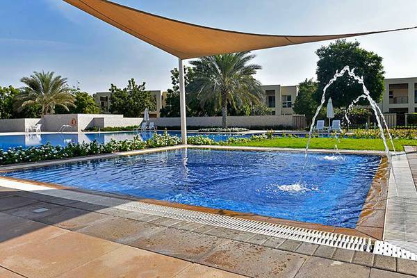 Außenpool im Jannah Hotels Resorts & Villas mit Sonnenschirm und Wasserfontäne.