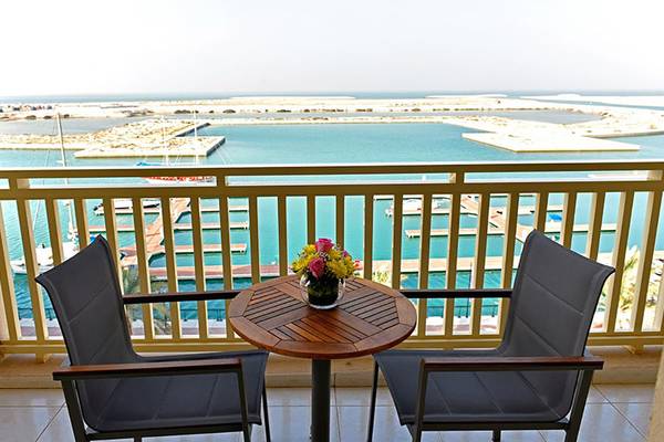 Ein Balkon mit Blick auf das Meer und eine Marina im Jannah Hotels Resorts & Villas.