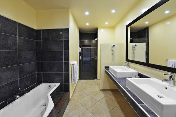 Badezimmer im LionsDive Beach Resort mit Badewanne und zwei Waschbecken.