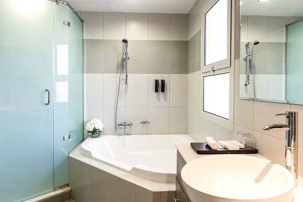 Badezimmer mit Badewanne und Dusche in einem Jannah Hotel.