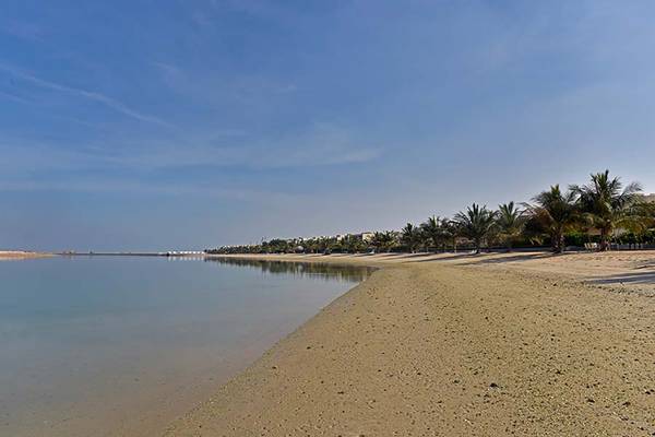 Strand mit flachem Wasser und Palmen bei Jannah Hotels Resorts & Villas