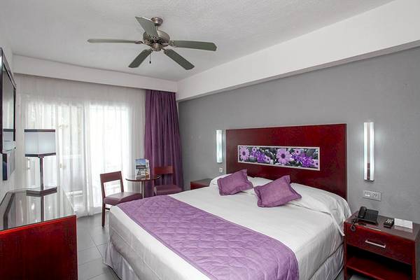 Hotelzimmer im Riu Naiboa mit Bett, Deckenventilator und Fernseher.