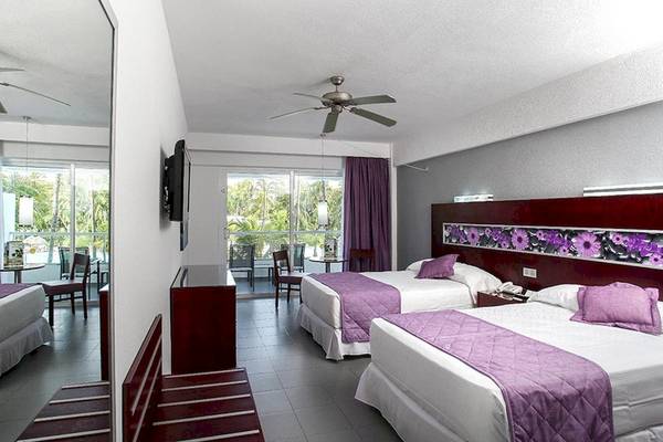 Zwei Betten mit violetten Decken in einem Hotelzimmer des Riu Naiboa