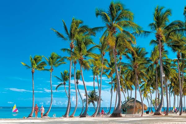 Strand mit Palmen und Leuten vor dem Riu Naiboa Hotel.