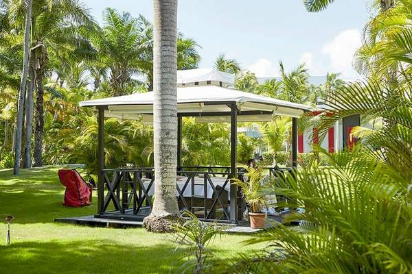 Gazebo im Garten des Riu Naiboa Hotels, umgeben von Palmen und grünem Rasen.
