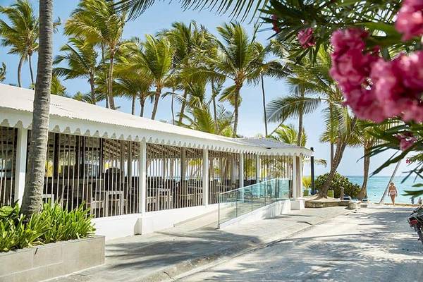 Außenansicht des Riu Naiboa Hotels mit Palmen und Strand im Hintergrund.