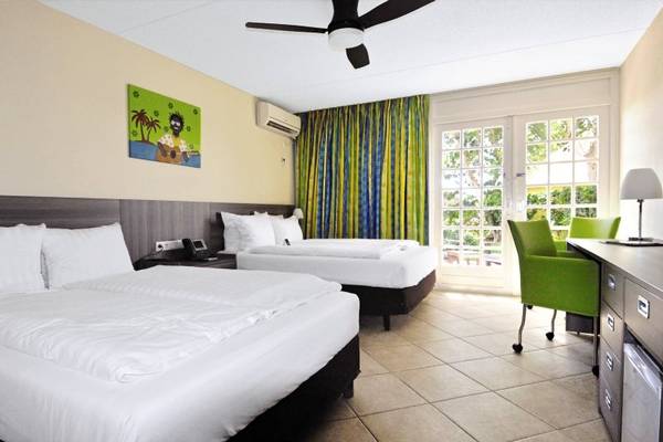 Doppelbettzimmer im LionsDive Beach Resort Hotel mit Klimaanlage, Bettwäsche und Schreibtisch.