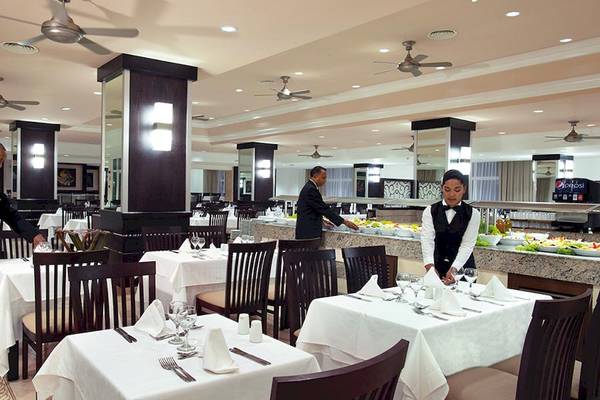 Innenbereich eines Restaurants im Riu Naiboa Hotel mit gedeckten Tischen und Angestellten, die Salate servieren.
