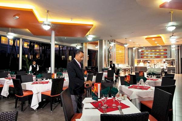 Innenansicht des Restaurants im Riu Naiboa Hotel mit gedeckten Tischen und servierenden Kellnern.