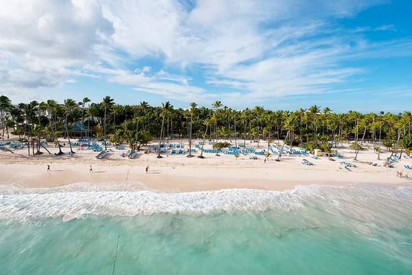 Luftaufnahme des Riu Naiboa Hotels mit breitem weißen Sandstrand und blauem Himmel.