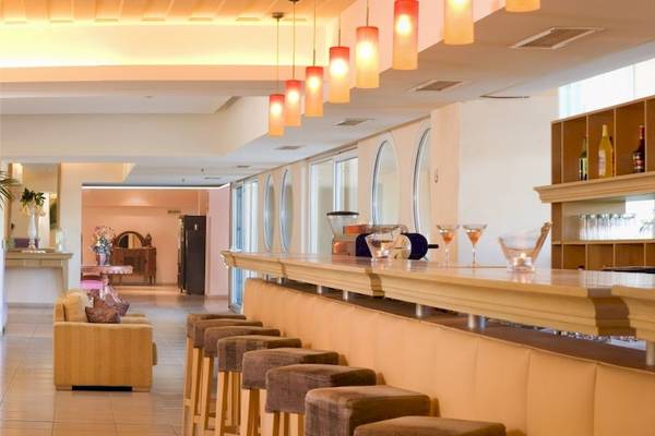 Rezeption und Bar des Ariti Grand Hotel Corfu mit gepolsterten Barhockern und hängenden Lampen.